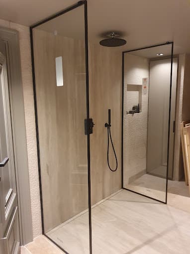 Douche à l’italienne avec paroi vitrée à profilés noirs et grand carrelage beige